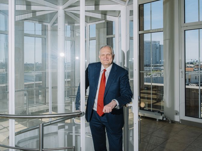 Leibniz-Präsident Christoph M. Schmidt steht verschmitzt lächelnd im gläsernen Turm auf dem Dach der Leibniz-Geschäftsstelle.