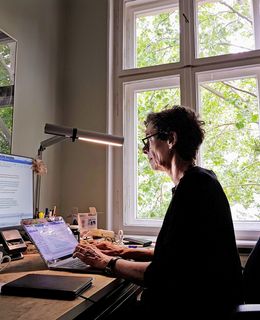 Jeanette Hofmann arbeitet am Bildschirm an ihrem Schreibtisch am Fenster.