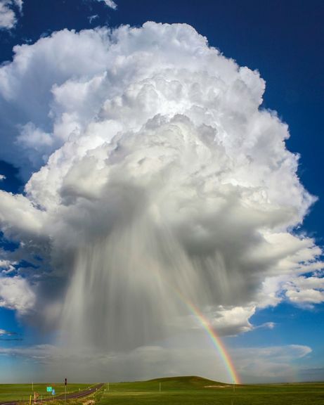 Große Regenwolke am Himmel und ein Regenbogen.